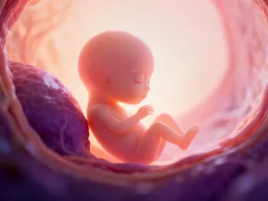 Szklana butelka z odciągniętym mlekiem matki o naturalnym, kremowym odcieniu, stojąca na jasnym drewnianym stole.